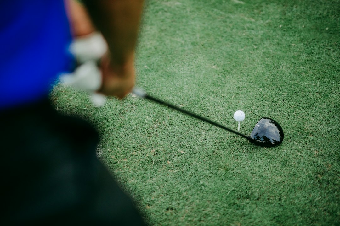 A golf ball sitting on the grass beside a driver