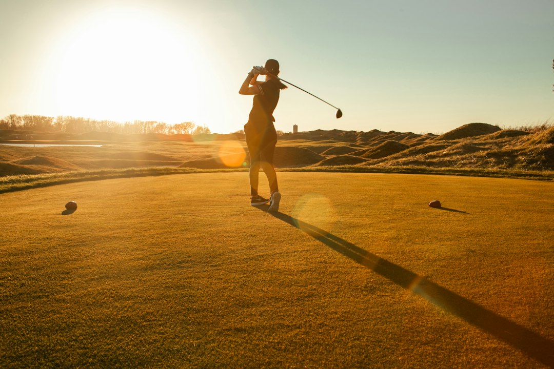 A golfer teeing off on an autumn morning
