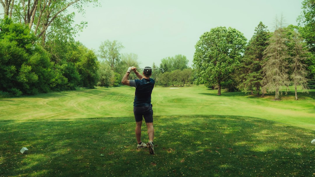 A golfer playing a shot on a green in summer light