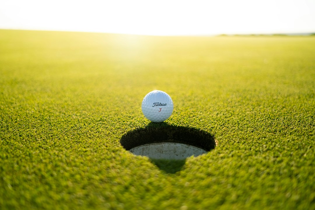 A golf ball resting on close-cut grass before an iron shot