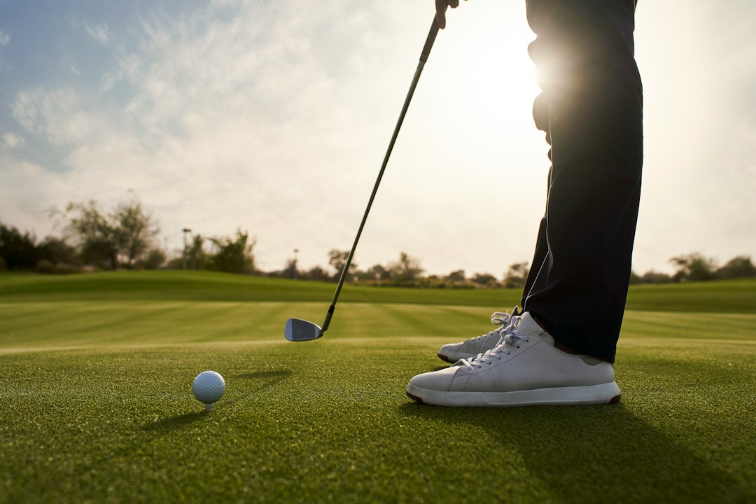 A golfer putting a ball on the green