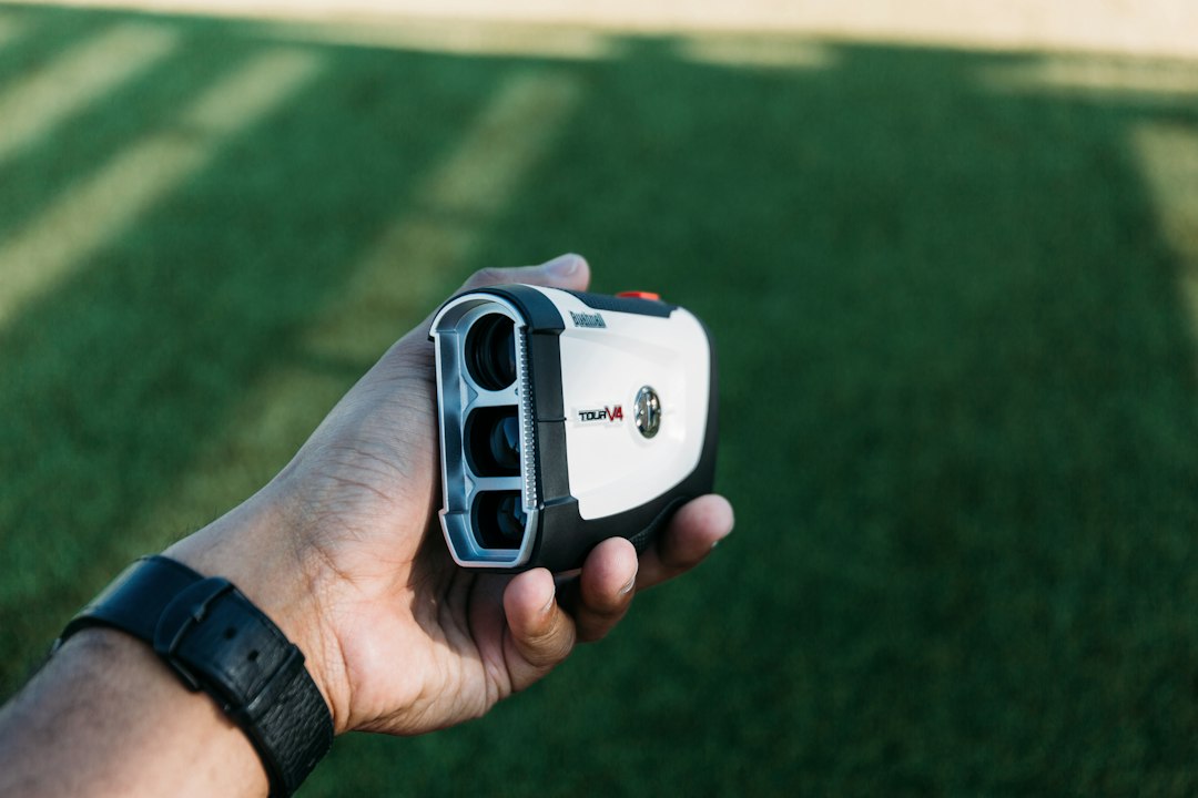 Hand holding a golf rangefinder in daylight