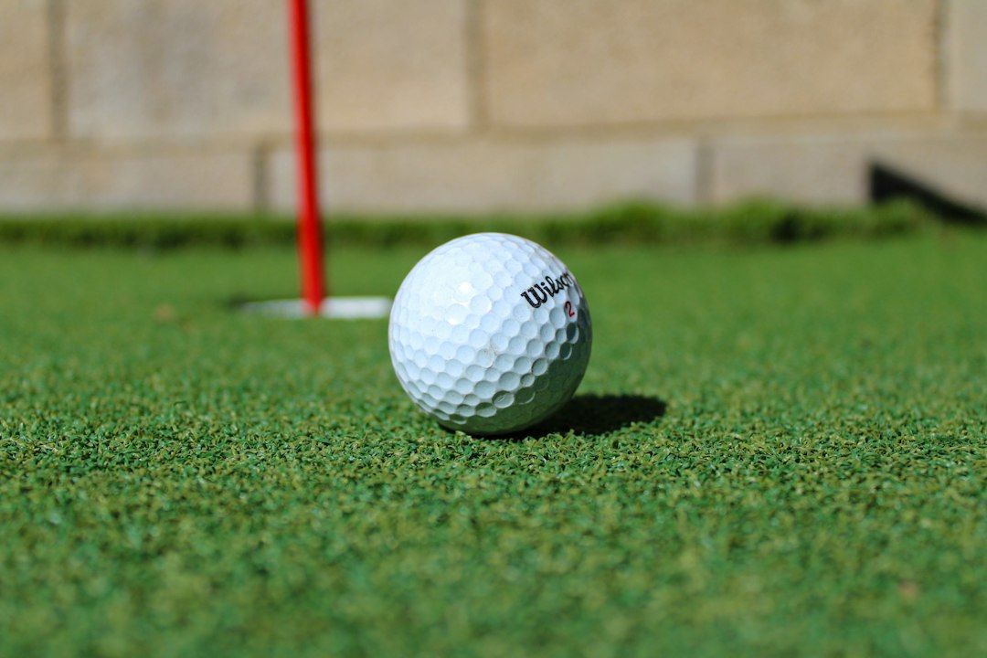 A golf ball on the putting green beside the hole